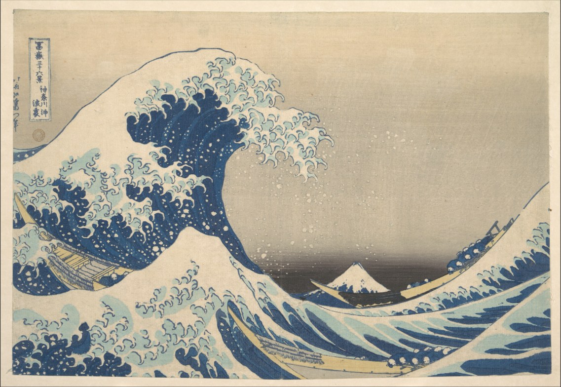 Woodblock print: a huge blue wave with claw-like foam curls over three boats; a small snow-capped Mount Fuji sits in the trough.