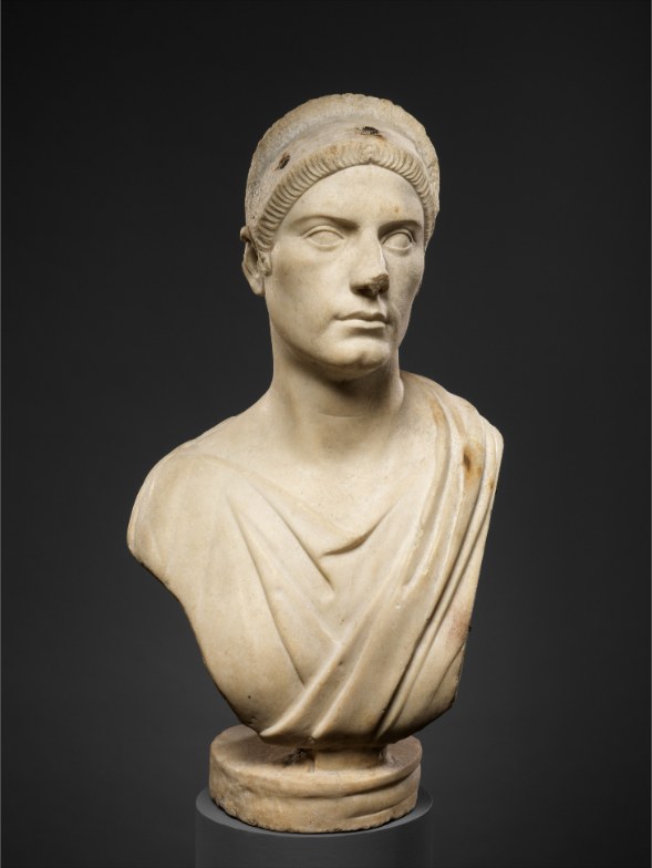 Marble bust of a woman with a plain band over the hair, draped garment, direct gaze; small ancient holes above the forehead.